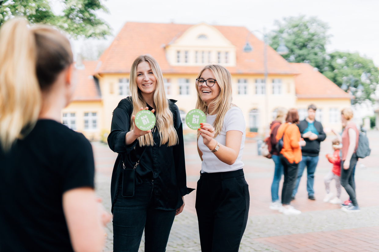 Zwei Frauen halten lächelnd Bierdeckel 