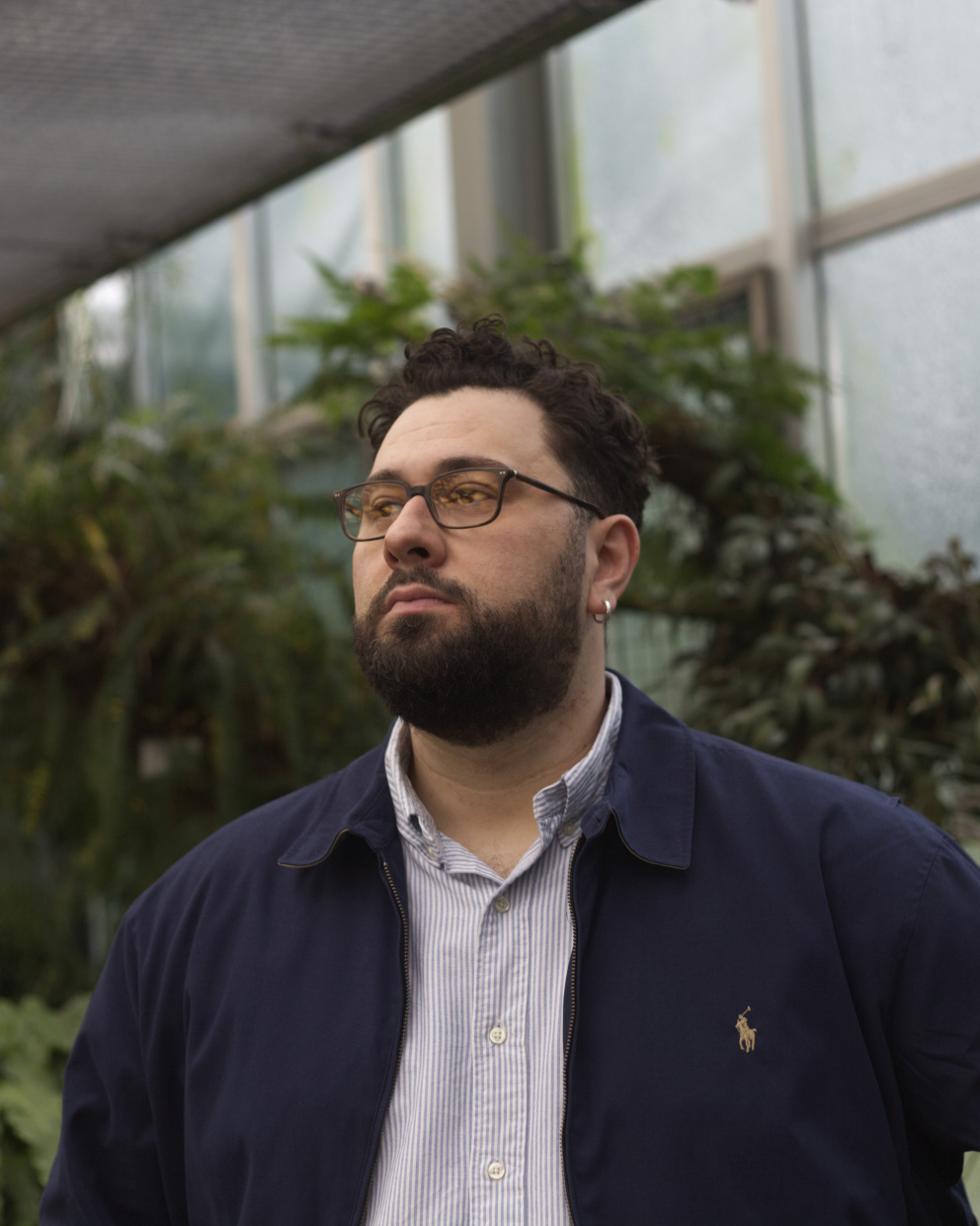 Mann mit Brille und dunklem Blazer vor grünem Hintergrund.