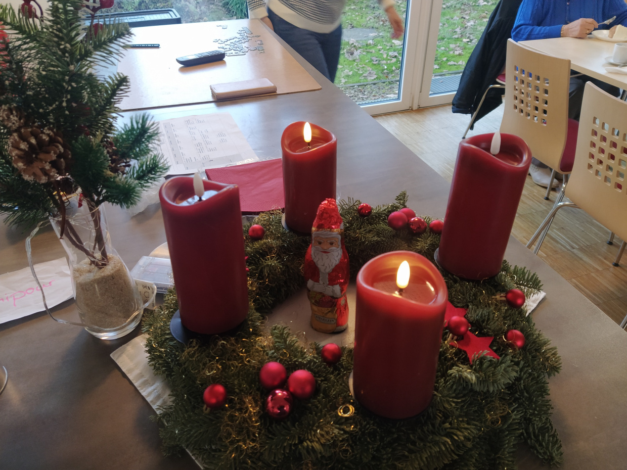 Ein Adventskranz mit roten Kerzen und einem Schokoweihnachtsmann in der Mitte
