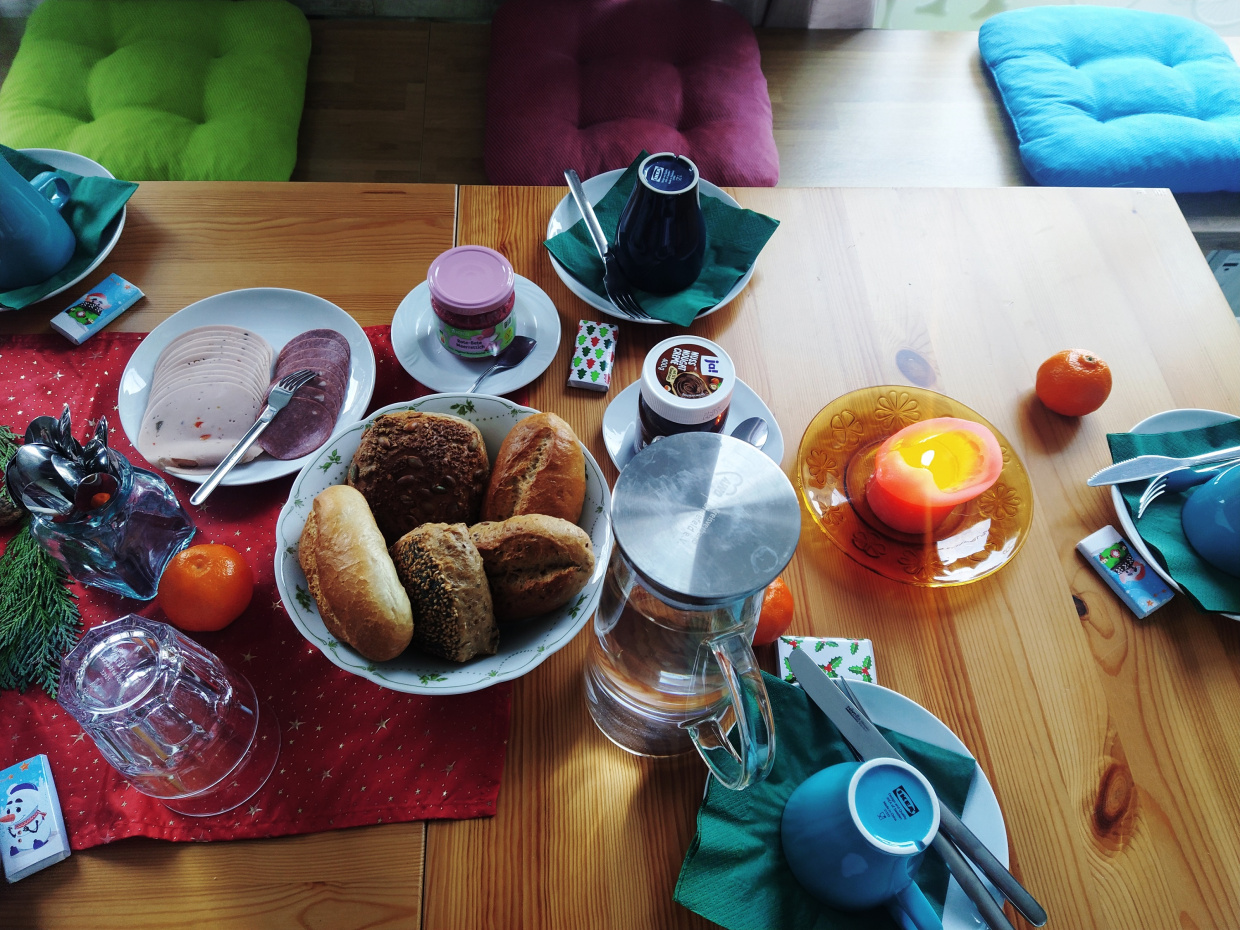 ein mit Brötchen, Konfitüre, Heißgetränken gedeckter Tisch