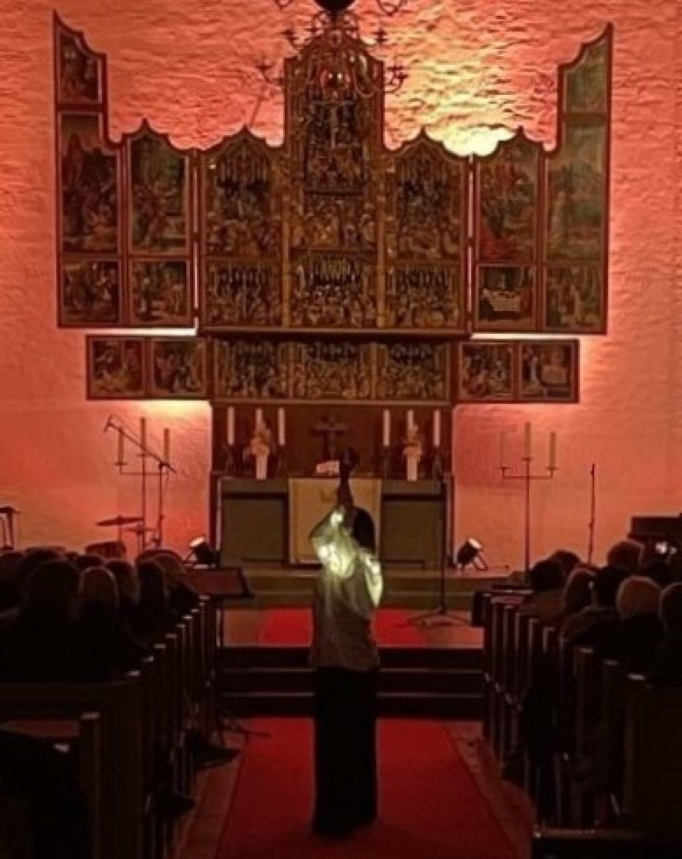Inennansicht der verdunkelten im warmes rot getauchten Kirche mit leuchtender Tänzerin