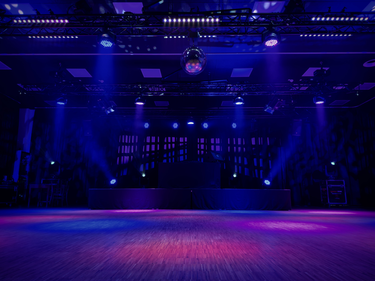 Das bild zeit eine bunt beleuchtete Tanzfläche und Bühne. In der Mitte hängt an der Decke eine Disko