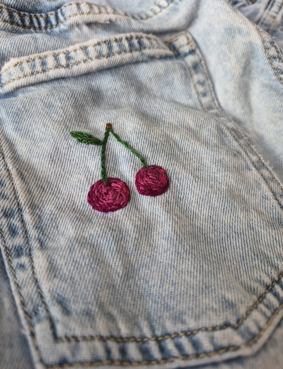 Gestickte Kirsche auf einer Jeanshose
