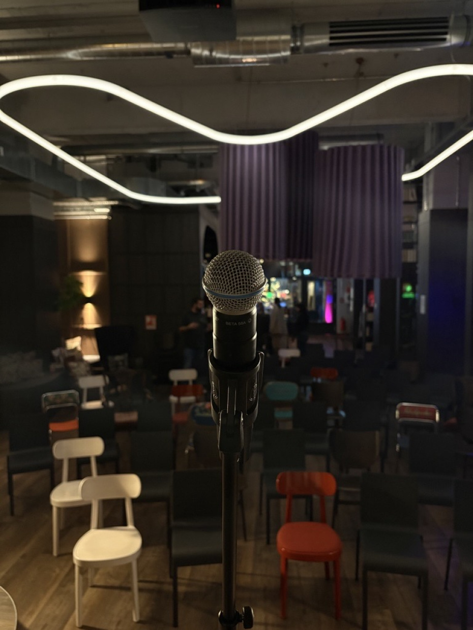 Mikrofonständer auf Bühne vor leeren Stühlen im Coworking Space bei "Heins arbeitet".