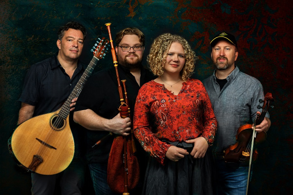 Drei Musiker und eine Musikerin stehen zusammen mit ihren Folk-Instrumenten