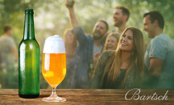 Grüne Bierflasche und gefülltes Glas mit Freundesgruppe im Hintergrund.