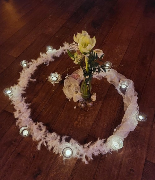 Blütenkranz aus weißen Blüten mit gelbem Wildkraut in der Mitte auf Holzgrund.