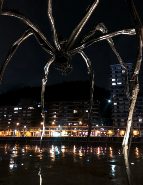 Das Bild zeigt die Spinnenskulptur "Maman" von Louise Bourgeois in Bilbao, bei Nacht, am Flussrand.