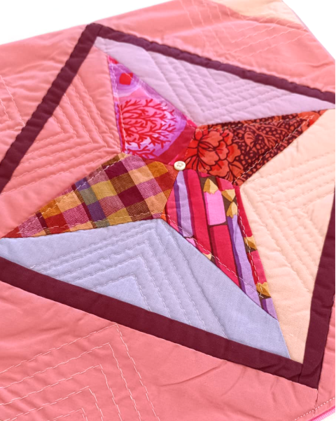 Ausschnitt eines Patchwork-Quilt in rosa, rot und lila.