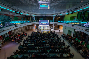 Großer Saal mit Publikum und Bühne unter moderner Beleuchtung.