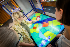 Frauen blicken auf ein großes Display.